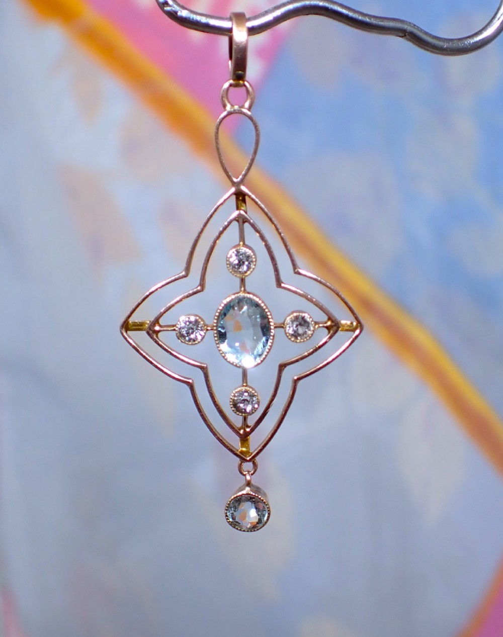 An openwork 9ct gold Edwardian pendant set with a central oval aquamarine, white sapphires, and a suspended aquamarine drop. View IV