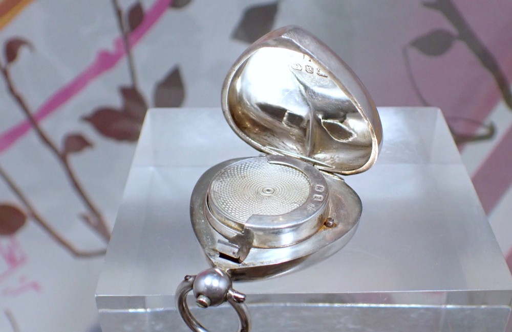 An open heart-shaped Victorian sterling silver sovereign holder showing an engine-turned internal spring mechanism and official hallmarks.