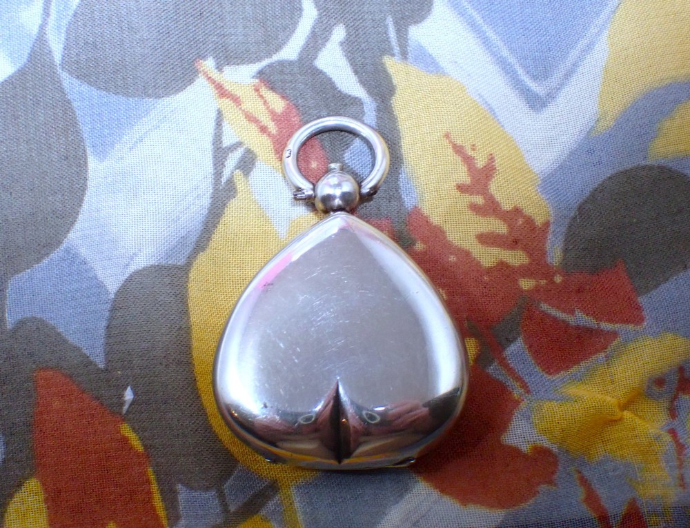 An open heart-shaped Victorian sterling silver sovereign holder showing an engine-turned internal spring mechanism and official hallmarks. View II