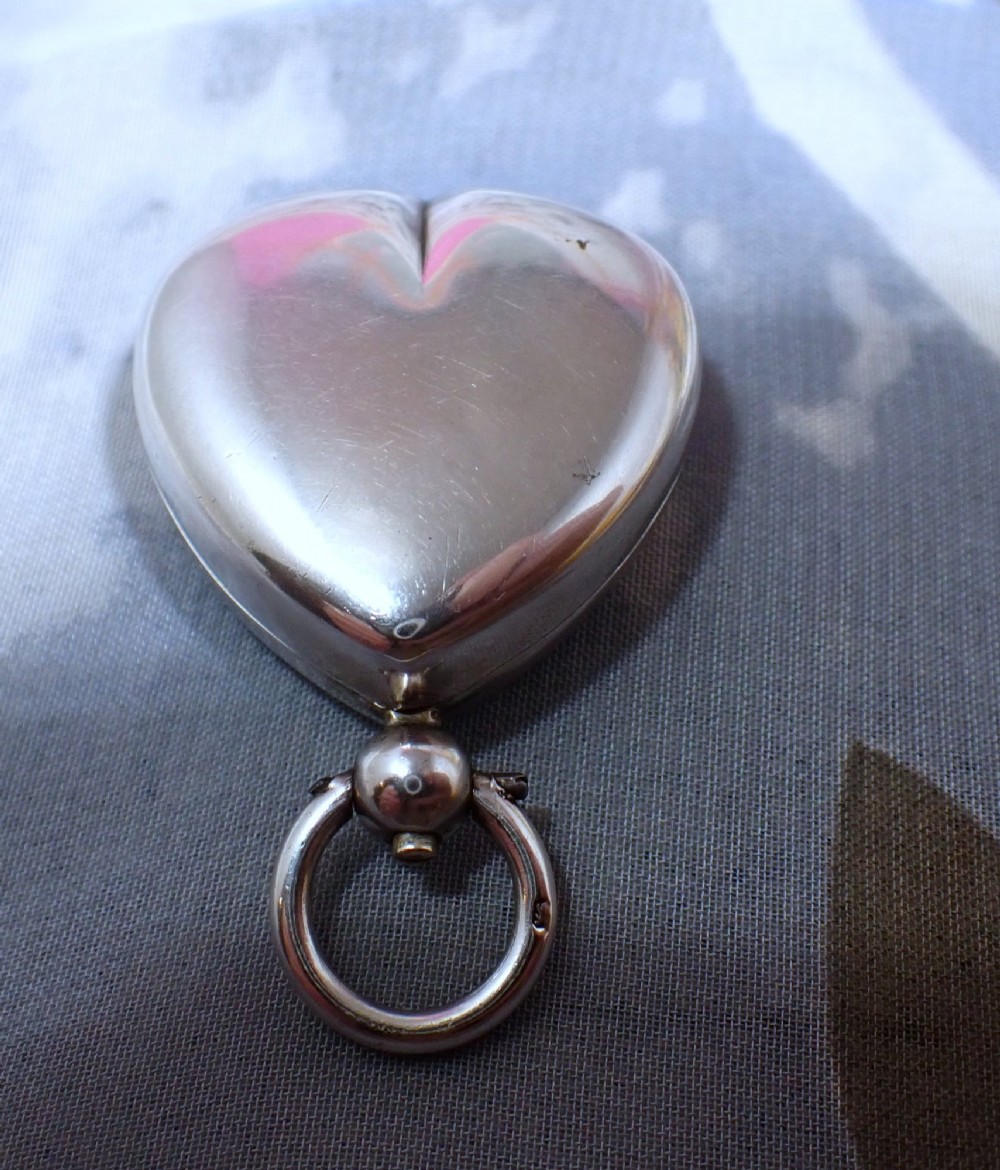 An open heart-shaped Victorian sterling silver sovereign holder showing an engine-turned internal spring mechanism and official hallmarks. View IV
