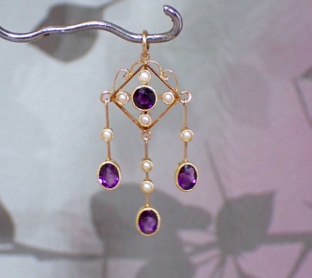 An Art Nouveau 15ct yellow gold openwork diamond-shaped pendant featuring a central round amethyst, seed pearls, and three dangling purple amethyst drops. View II