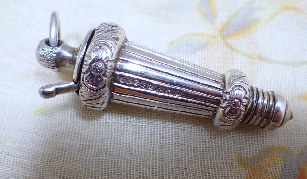 An ornate antique Edwardian sterling silver whistle pendant featuring engraved floral motifs, fluted detailing, and visible English silver hallmarks.