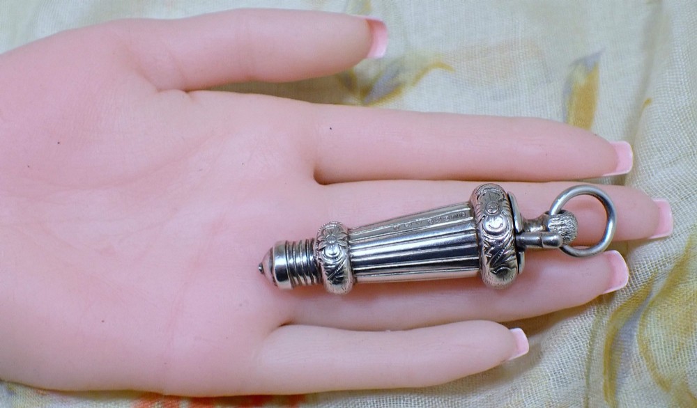 An ornate antique Edwardian sterling silver whistle pendant featuring engraved floral motifs, fluted detailing, and visible English silver hallmarks. View II