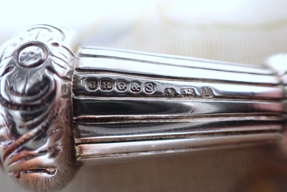 An ornate antique Edwardian sterling silver whistle pendant featuring engraved floral motifs, fluted detailing, and visible English silver hallmarks. View V
