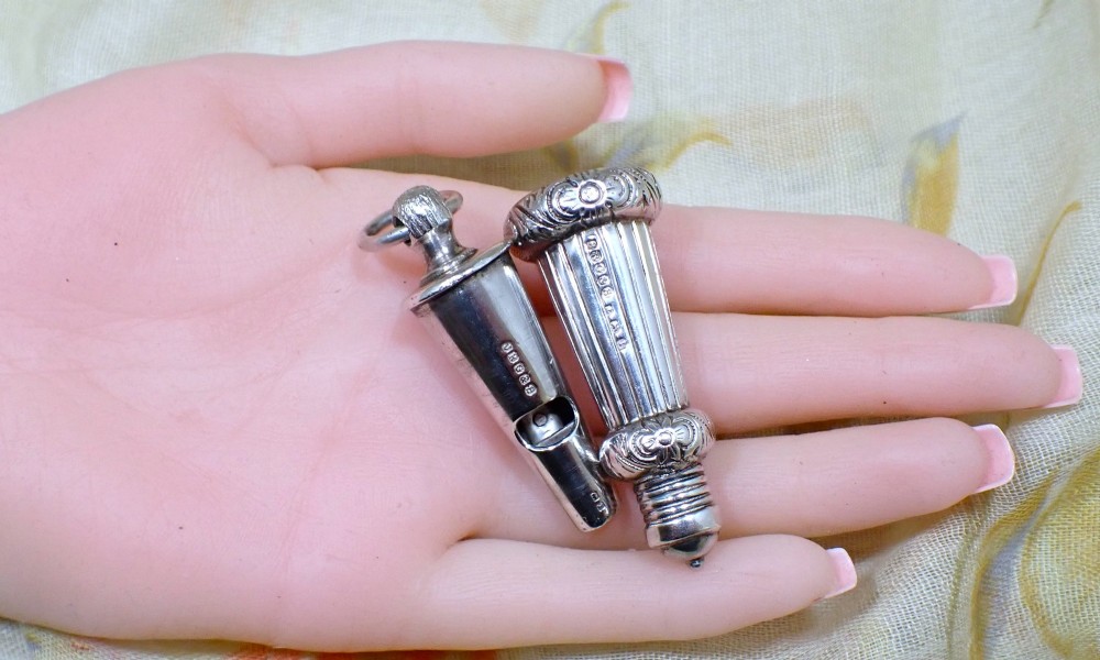 An ornate antique Edwardian sterling silver whistle pendant featuring engraved floral motifs, fluted detailing, and visible English silver hallmarks. View VI