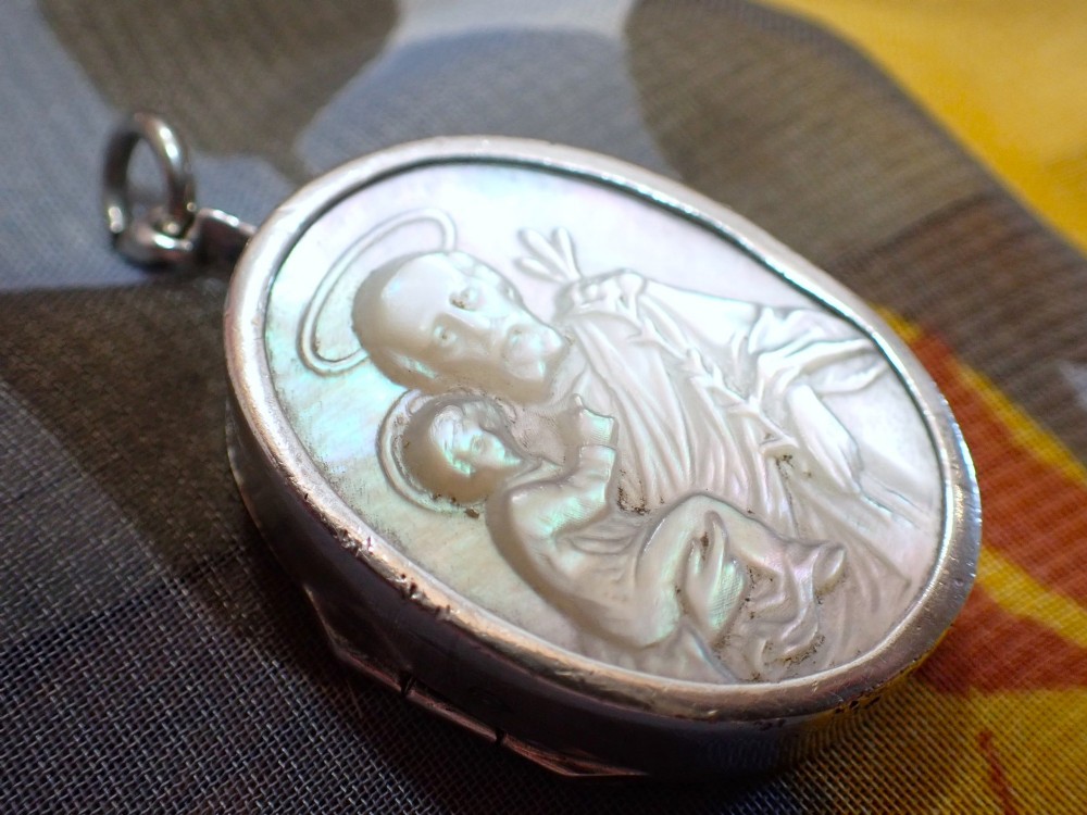 An oval Edwardian silver locket featuring a carved mother of pearl relief depicting Saint Christopher carrying the Christ child. View II
