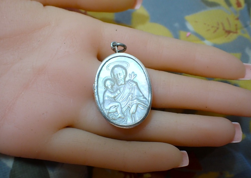 An oval Edwardian silver locket featuring a carved mother of pearl relief depicting Saint Christopher carrying the Christ child. View IV