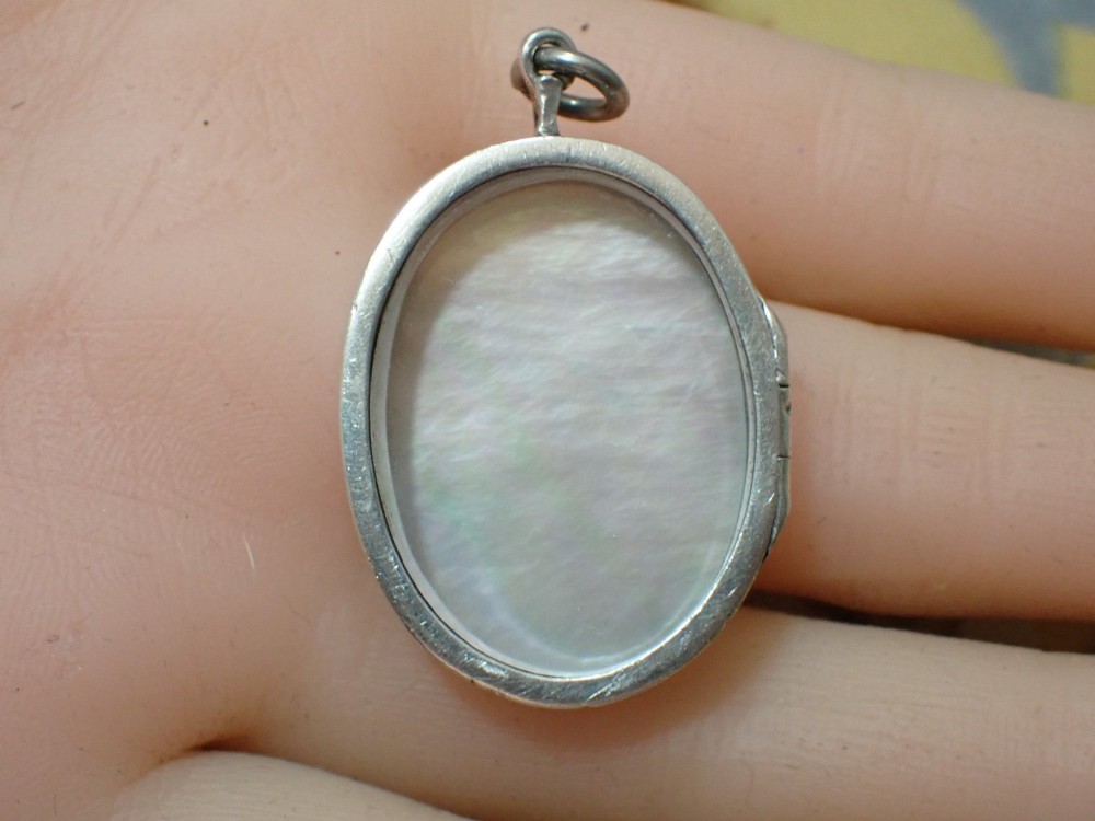 An oval Edwardian silver locket featuring a carved mother of pearl relief depicting Saint Christopher carrying the Christ child. View V