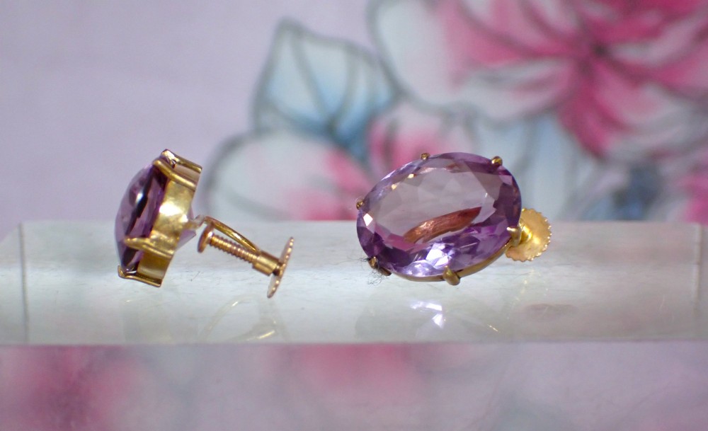 A pair of Edwardian 9ct yellow gold stud earrings set with oval faceted light purple amethyst gemstones and screw-back fastenings. View II