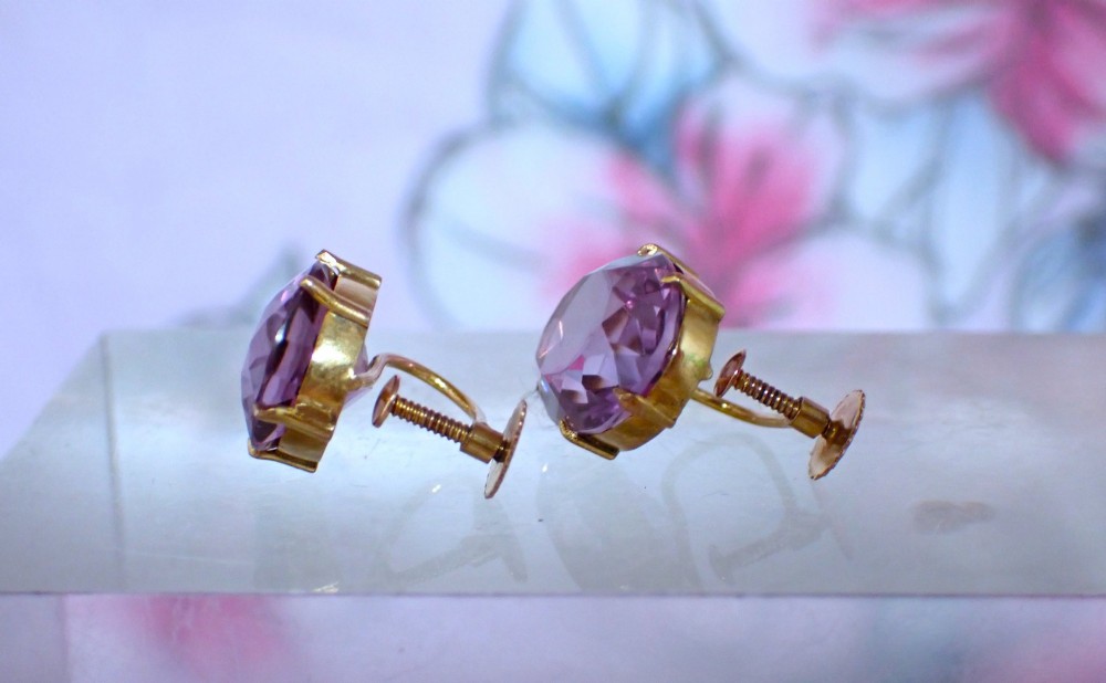 A pair of Edwardian 9ct yellow gold stud earrings set with oval faceted light purple amethyst gemstones and screw-back fastenings. View V