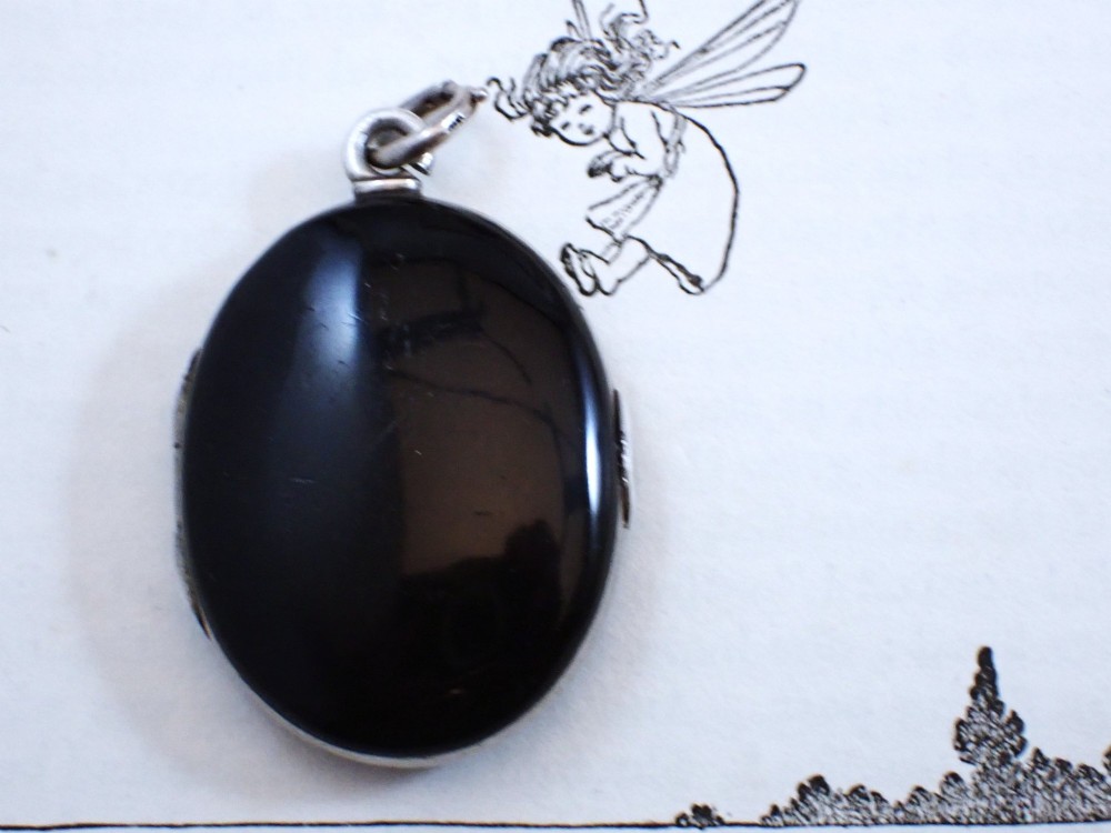 An oval Victorian black enamel locket with silver foliate inlay set with seed pearls, featuring a silver suspension bail. View II