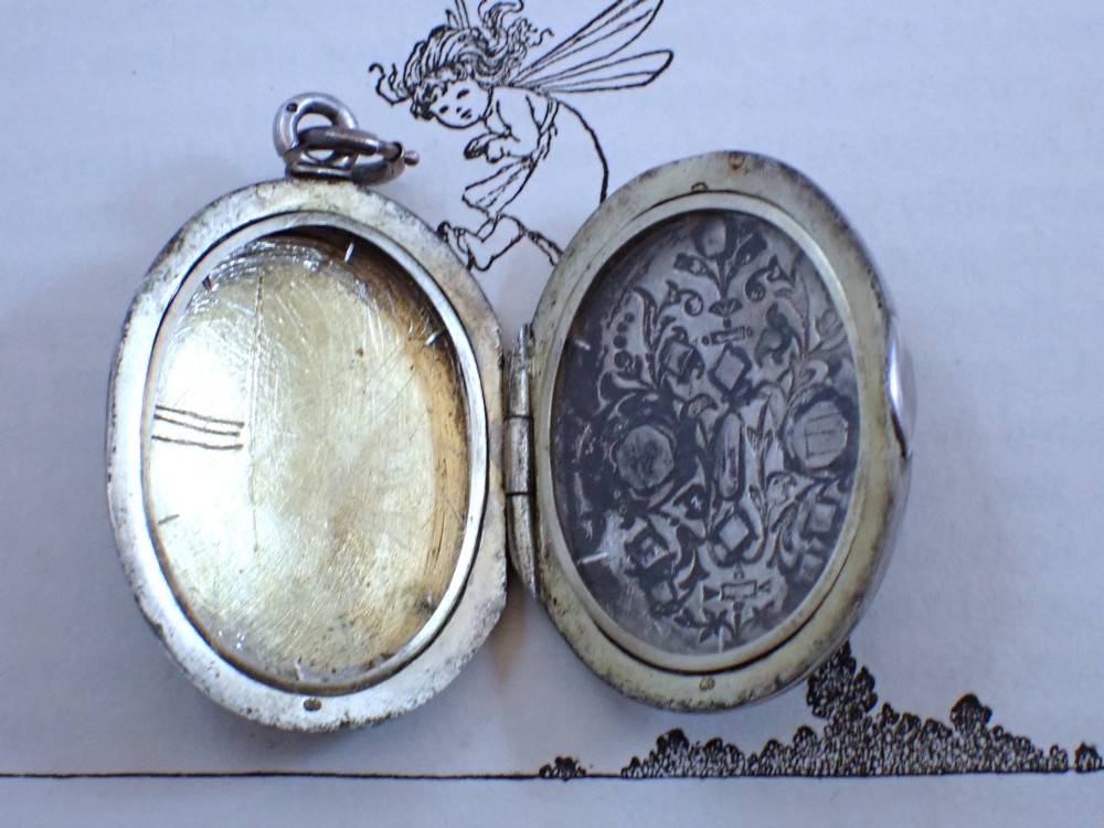 An oval Victorian black enamel locket with silver foliate inlay set with seed pearls, featuring a silver suspension bail. View III