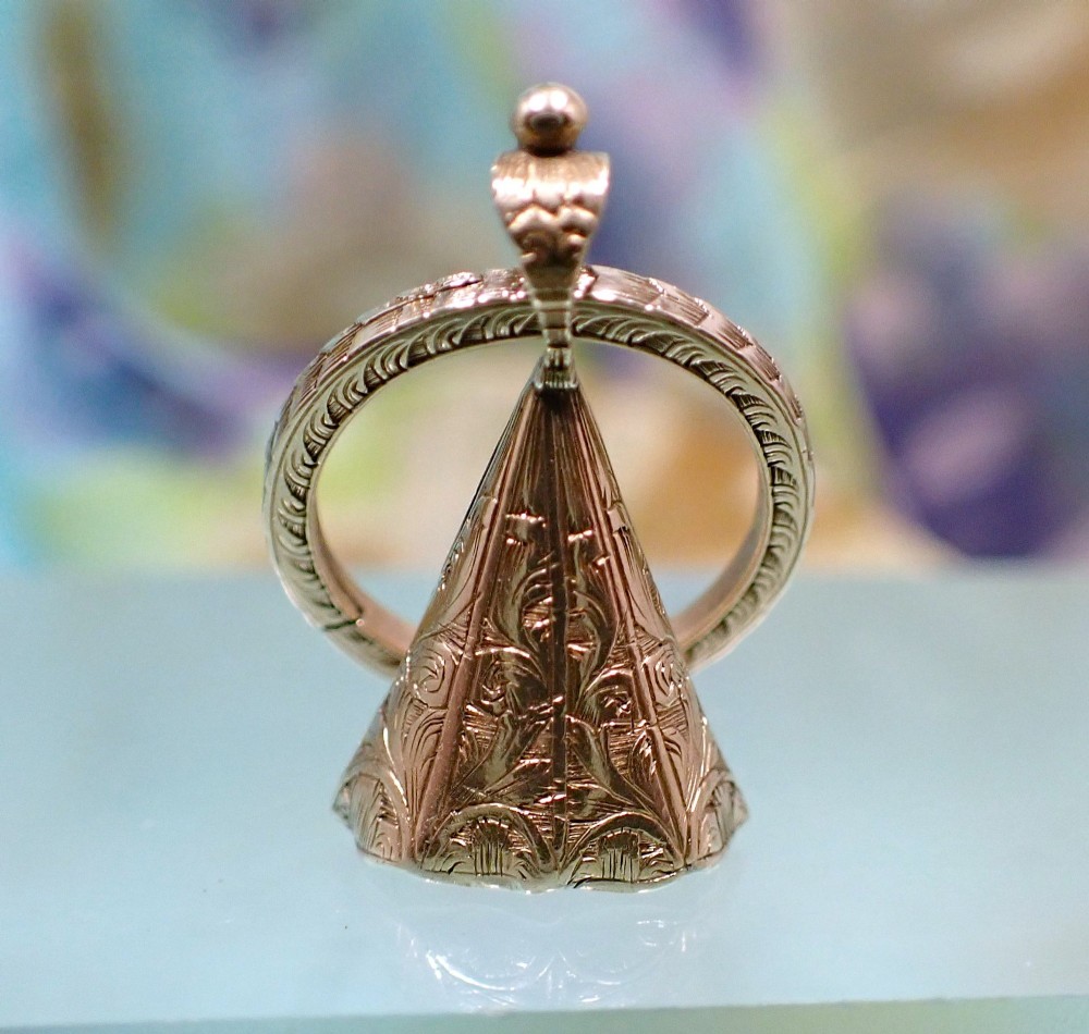 An antique 15ct gold conical fob seal featuring hand-engraved scroll motifs attached to a matching gold split ring.