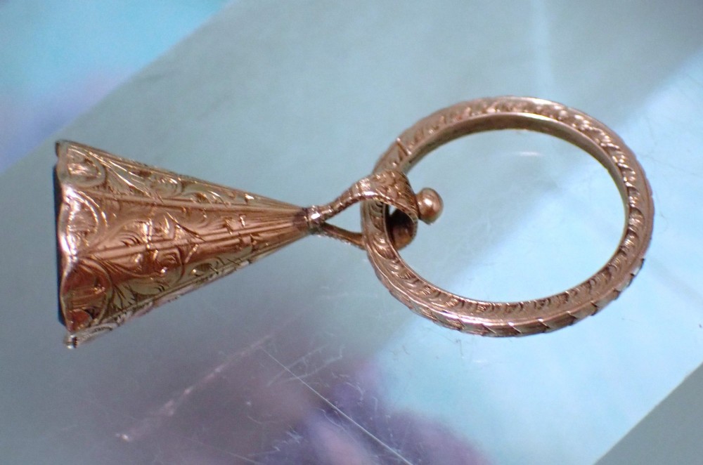 An antique 15ct gold conical fob seal featuring hand-engraved scroll motifs attached to a matching gold split ring. View II