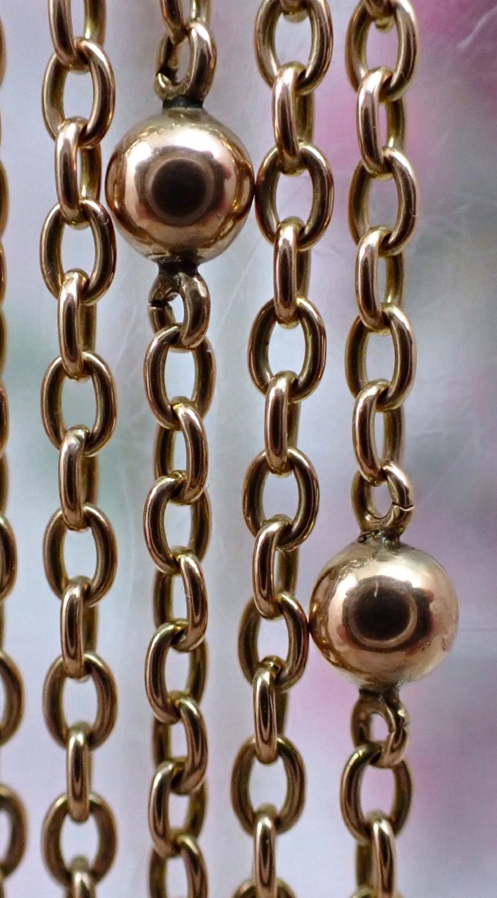 An antique Edwardian 15ct yellow gold guard chain coiled in a spiral, featuring small polished gold beads spaced along trace links and a spring ring clasp. View V