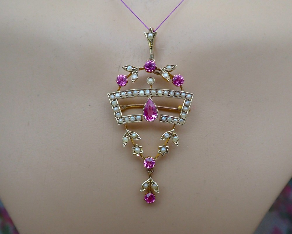 An Edwardian 15ct gold openwork pendant brooch set with natural pink tourmalines and seed pearls, featuring a central pear-cut gemstone drop. View IV