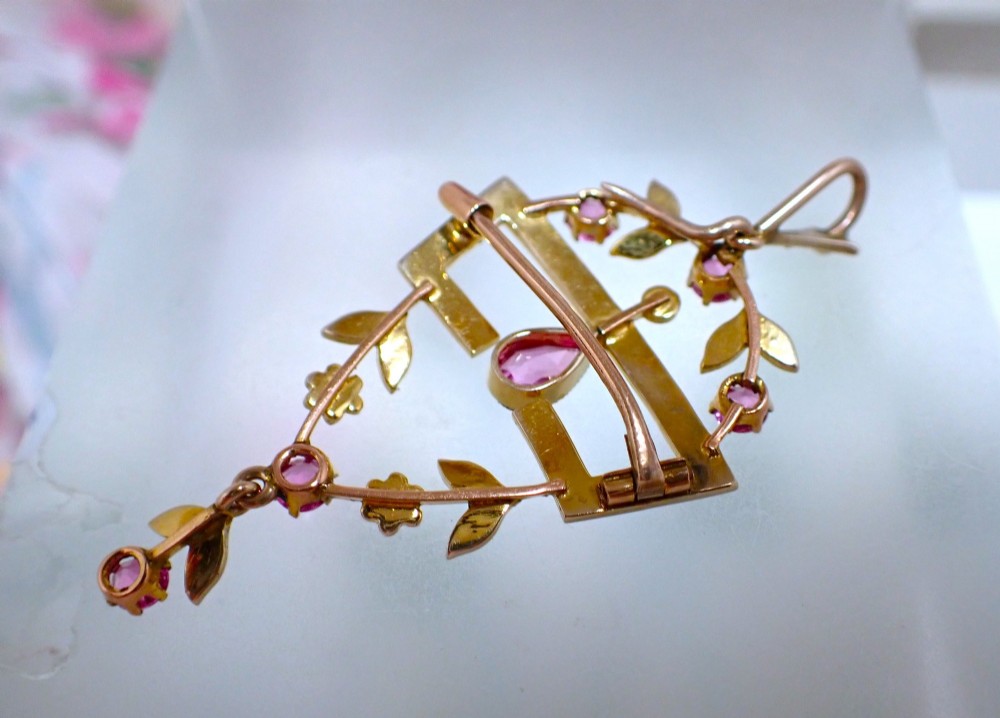 An Edwardian 15ct gold openwork pendant brooch set with natural pink tourmalines and seed pearls, featuring a central pear-cut gemstone drop. View V