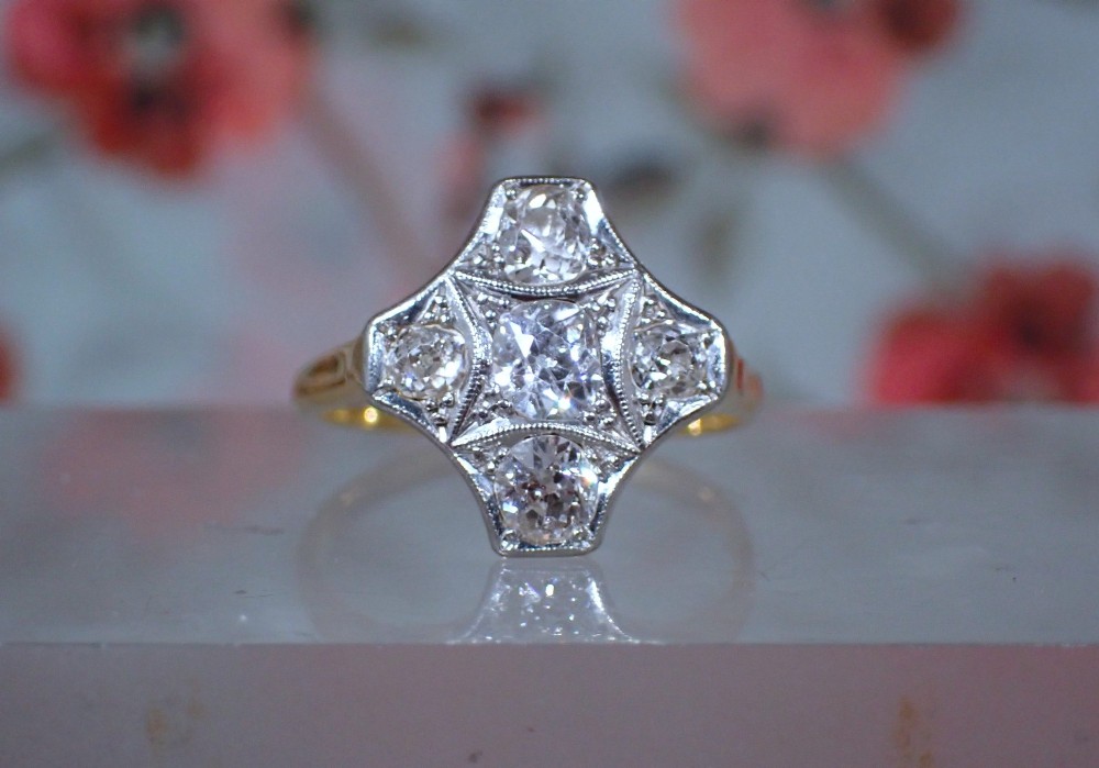 An Art Deco diamond ring featuring a geometric platinum plaque setting mounted on an 18ct yellow gold band.