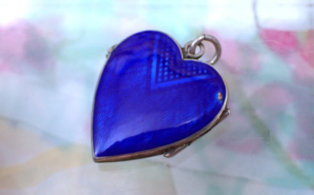 A heart-shaped silver locket featuring cobalt blue guilloche enamel decorated with a hand-painted floral rose garland motif. View III
