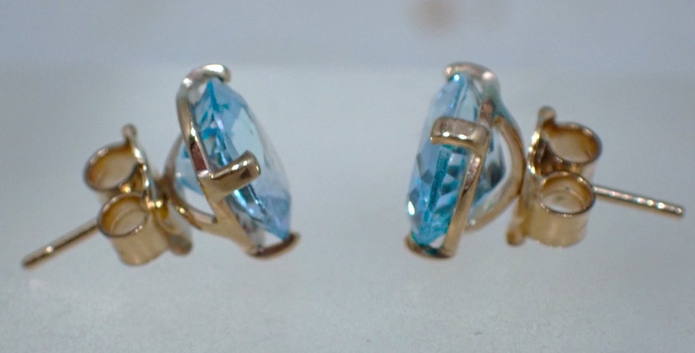 A pair of vintage gold stud earrings featuring oval-cut light blue aquamarine gemstones held within four-prong claw settings. View IV