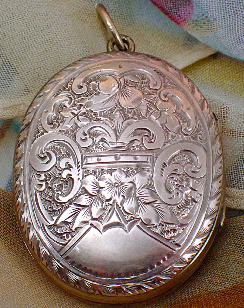 An oval Victorian rose gold back and front locket featuring intricate hand-engraved scrollwork and floral motifs with a top suspension loop. View II
