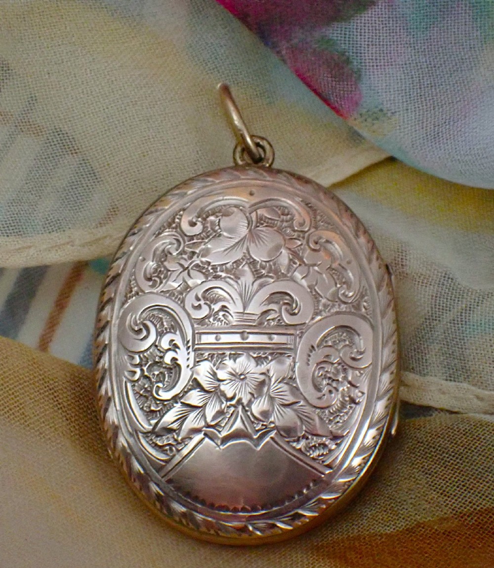 An oval Victorian rose gold back and front locket featuring intricate hand-engraved scrollwork and floral motifs with a top suspension loop.