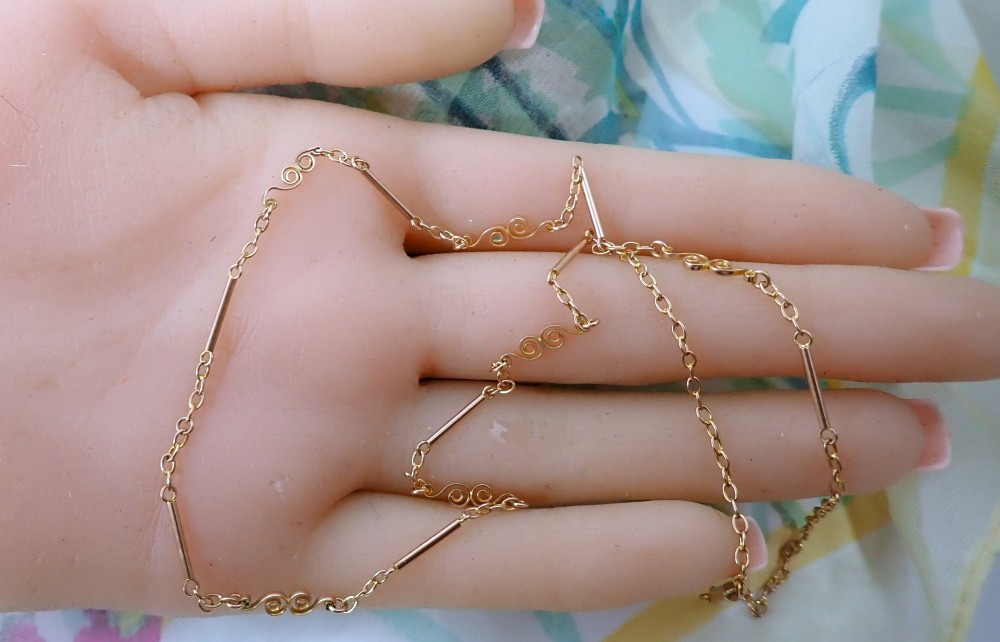An antique Victorian 9ct rose gold chain composed of alternating cylindrical bar links and coiled wirework scrolls. View VI