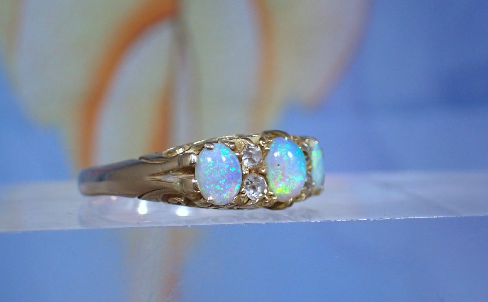 An Edwardian 18ct yellow gold ring set with three oval cabochon opals and small accent diamonds in a carved gallery. View III