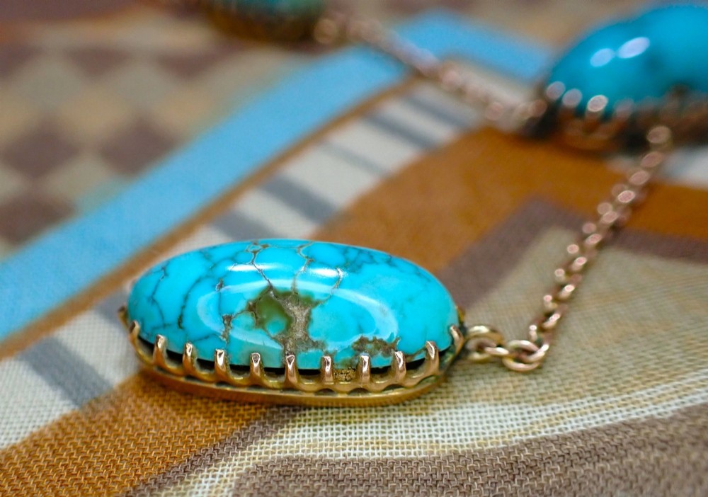 An Edwardian 9ct rose gold negligee necklace set with five oval matrix turquoise cabochons suspended on fine trace chains. View IV