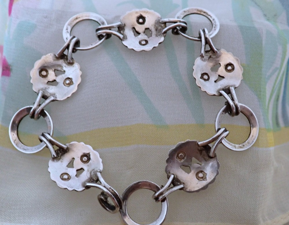 An Arts and Crafts sterling silver link bracelet featuring circular openwork panels decorated with colourful enamelled flowers and leaves. View II