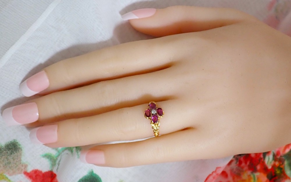 An antique Victorian 15ct yellow gold ring featuring four oval almandine garnets centred around a single old-cut diamond with carved scroll shoulders. View XI