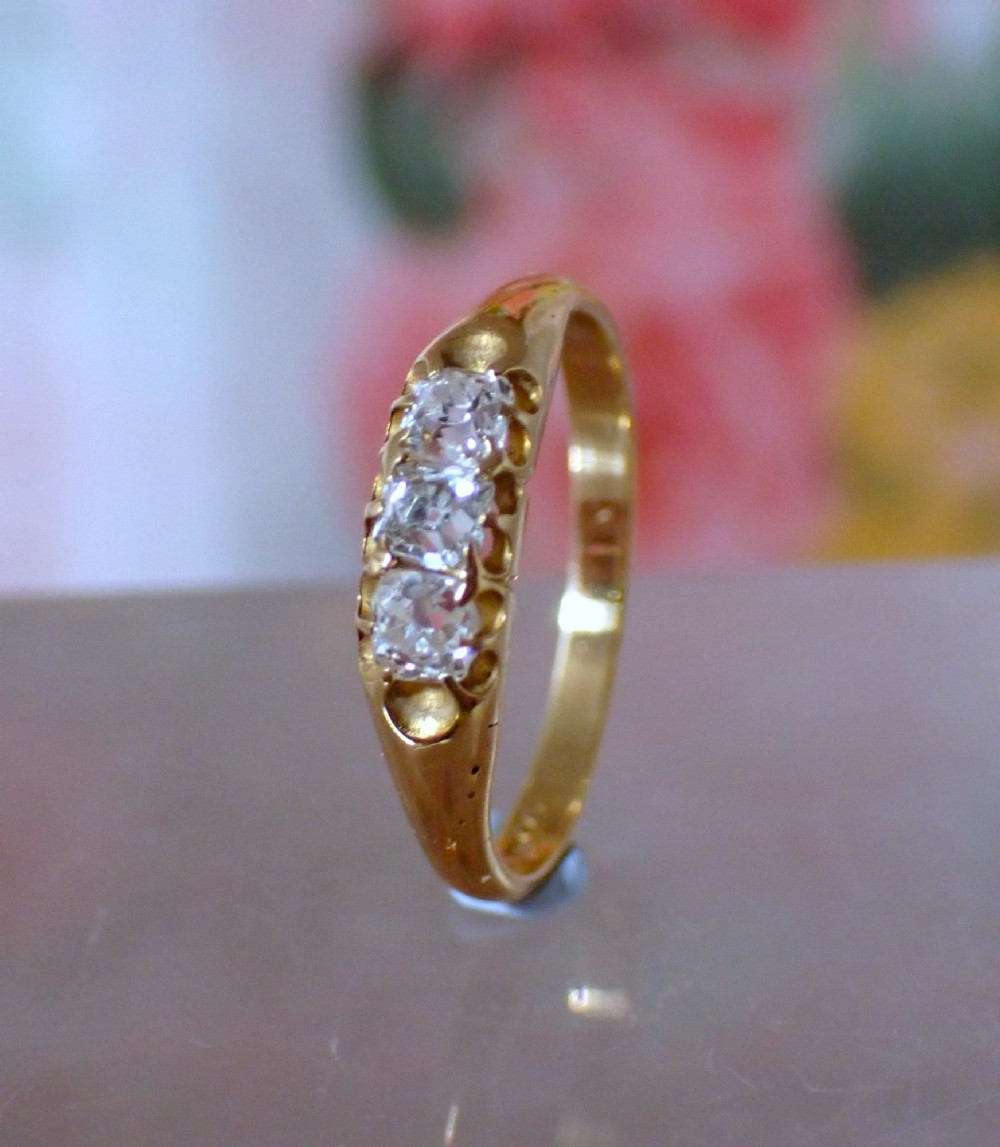 An 18ct yellow gold Victorian ring featuring three cushion cut diamonds set in a carved row along the band. View II