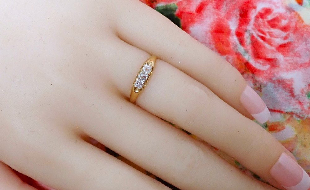 An 18ct yellow gold Victorian ring featuring three cushion cut diamonds set in a carved row along the band. View III