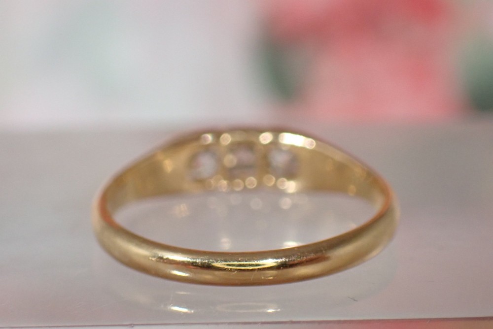 An 18ct yellow gold Victorian ring featuring three cushion cut diamonds set in a carved row along the band. View IV