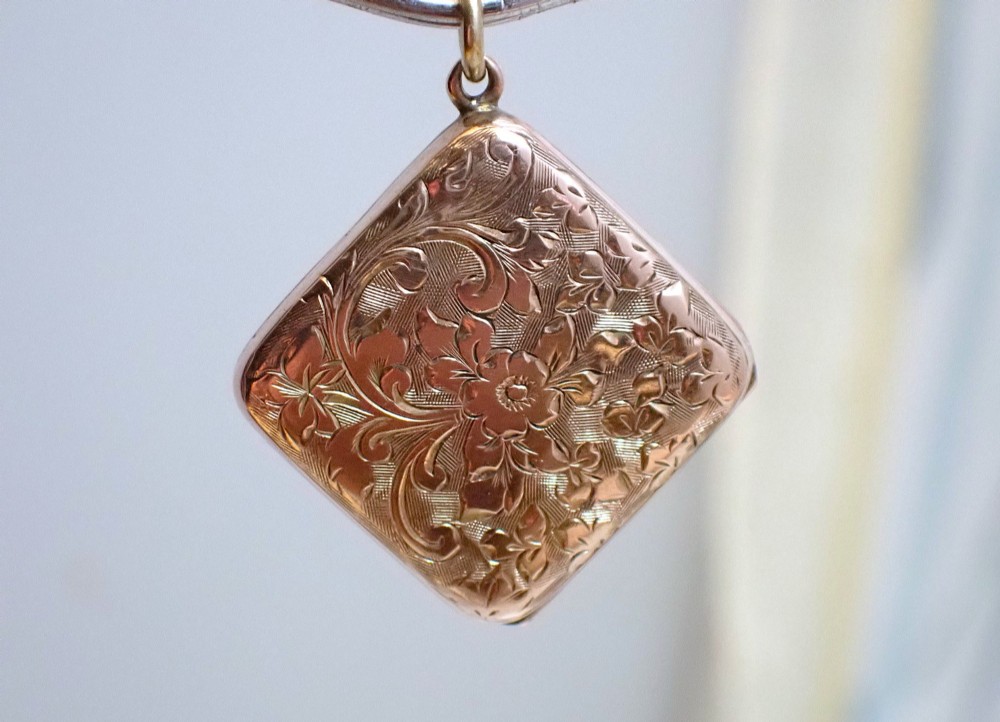 An antique Victorian square rose gold double fronted locket with hand engraved floral patterns and a heart cartouche. View IV