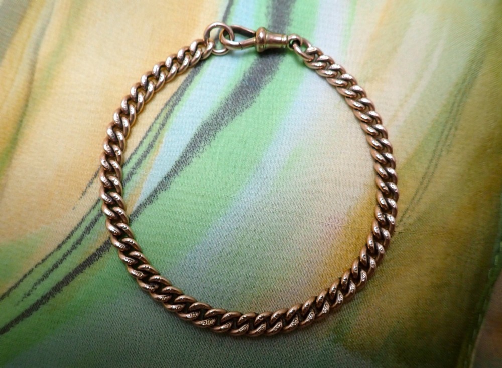 An Edwardian 9ct rose gold curb link bracelet featuring interlocking links and a traditional swivel clasp closure.