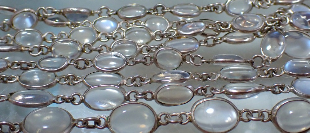 An antique Arts and Crafts sterling silver double-strand necklace featuring bezel-set oval cabochon moonstones linked together by wire chain loops. View III