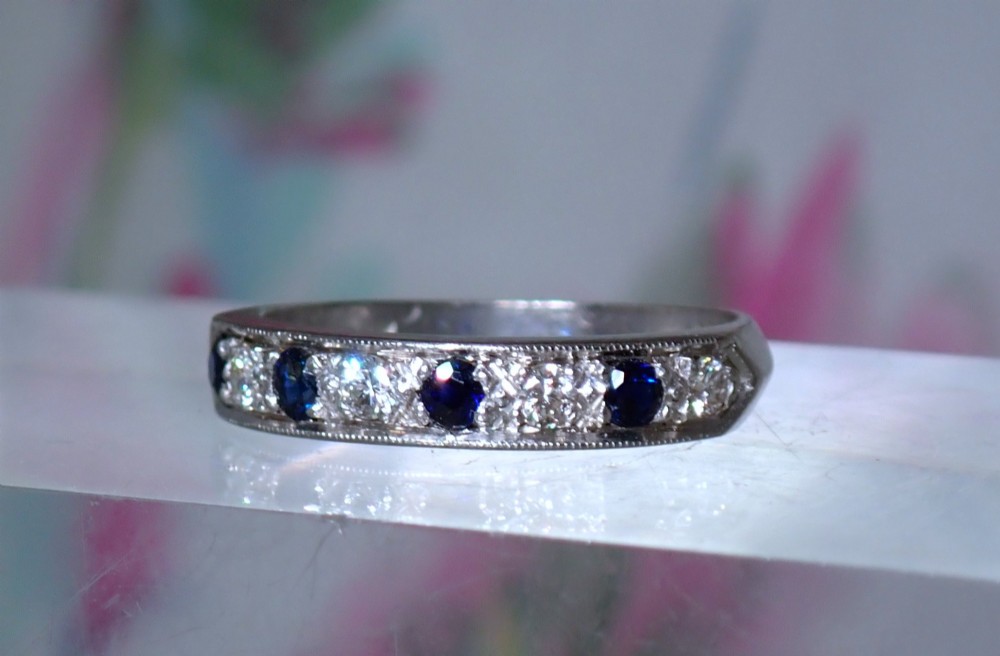 A vintage 18ct white gold half eternity ring featuring alternating round dark blue sapphires and clear diamonds along the band. View III