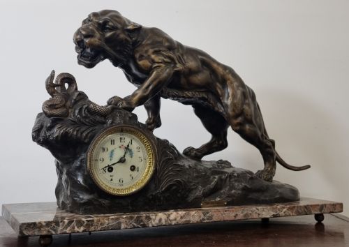 fig 2. A dark patinated bronze sculpture of a tiger fighting a serpent set upon a rock housing a round clock dial, all resting on a rectangular veined marble base.