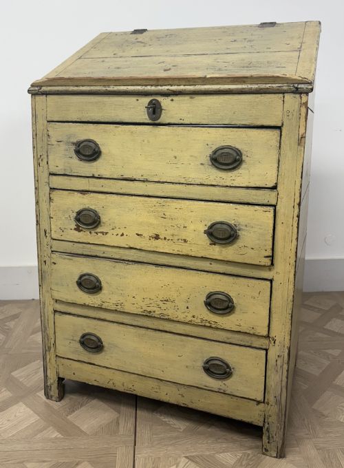 fig 1. A late 18th-century English provincial chest of four drawers with a distressed yellow painted finish, brass handles, and an angled writing slope top.
