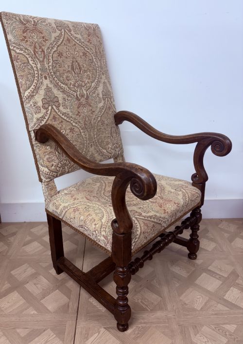 fig 1. A late 17th-century French walnut armchair featuring a tall patterned fabric backrest, curved scroll arms, and turned legs with stretchers.