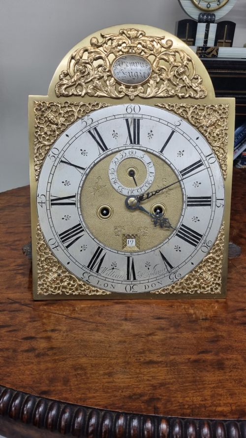 fig 1. An 18th-century green and gold Japanned longcase clock featuring hand-painted Chinoiserie landscapes, an arched brass dial, and gilt finials.