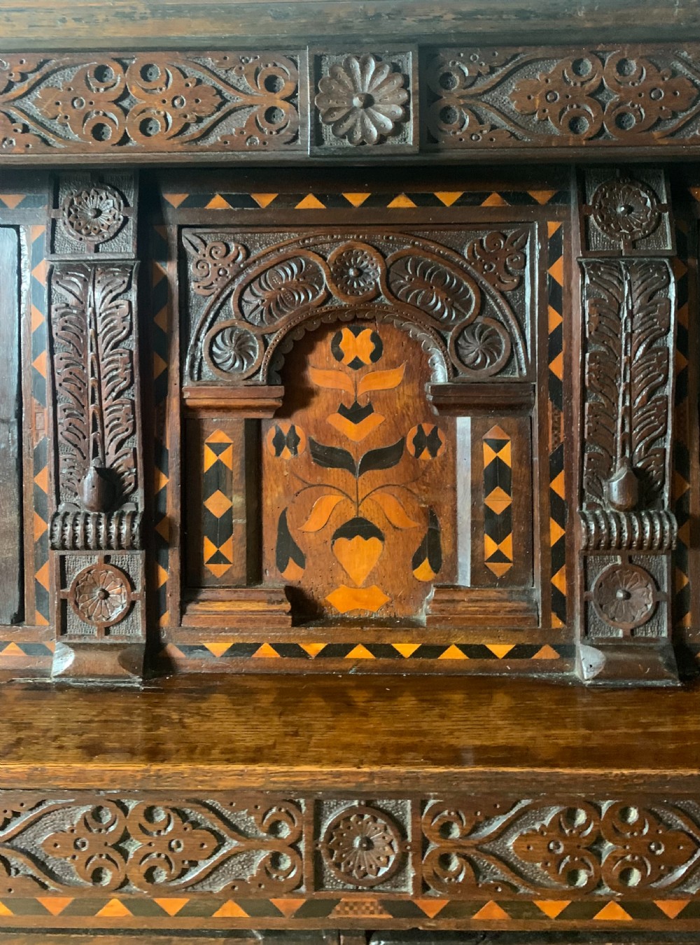A 17th-century Elizabethan carved oak court cupboard featuring inlaid geometric panels, cup-and-cover supports, and arcaded lower doors. View XI
