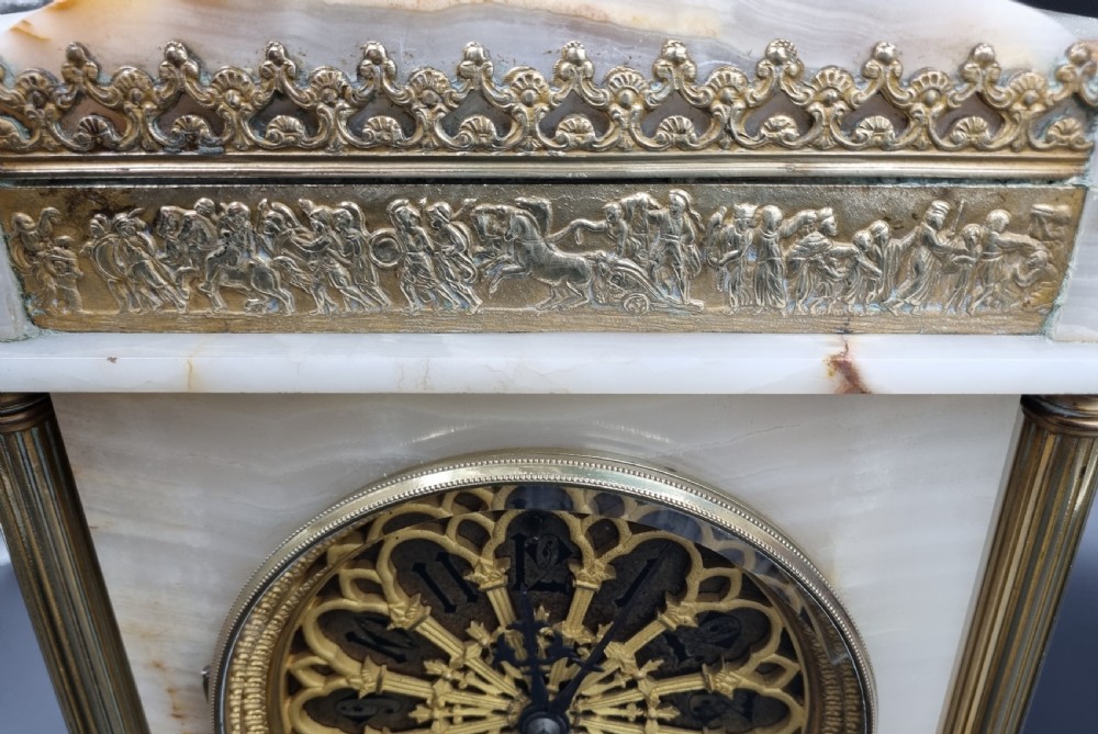A nineteenth-century cream onyx mantel clock featuring gilt bronze mounts, classical columns, a decorative pierced dial, and a small bust of William Shakespeare mounted at the top. View II