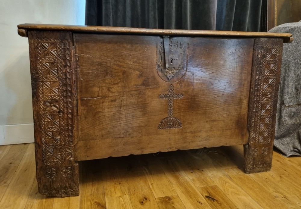 A dark stained oak coffer with carved geometric border panels, a central carved cross design, and a wrought iron escutcheon on the front. View V