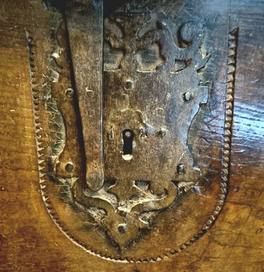 A dark stained oak coffer with carved geometric border panels, a central carved cross design, and a wrought iron escutcheon on the front. View VI