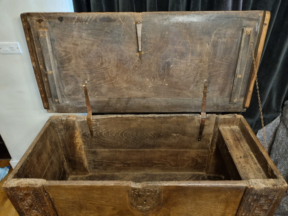 A dark stained oak coffer with carved geometric border panels, a central carved cross design, and a wrought iron escutcheon on the front. View IX