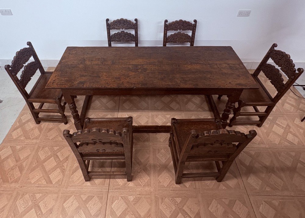 A dark oak refectory dining table paired with six matching carved wooden dining chairs set on a parquet floor. View IV