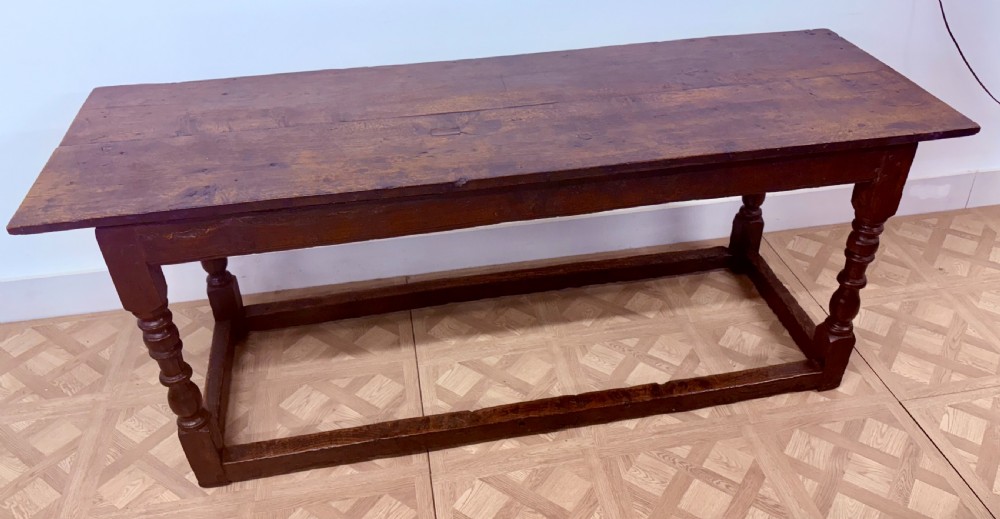 A dark oak refectory dining table paired with six matching carved wooden dining chairs set on a parquet floor. View III