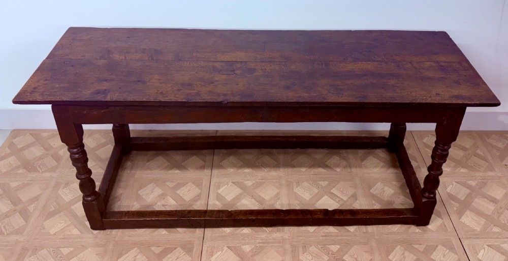 A dark oak refectory dining table paired with six matching carved wooden dining chairs set on a parquet floor. View II
